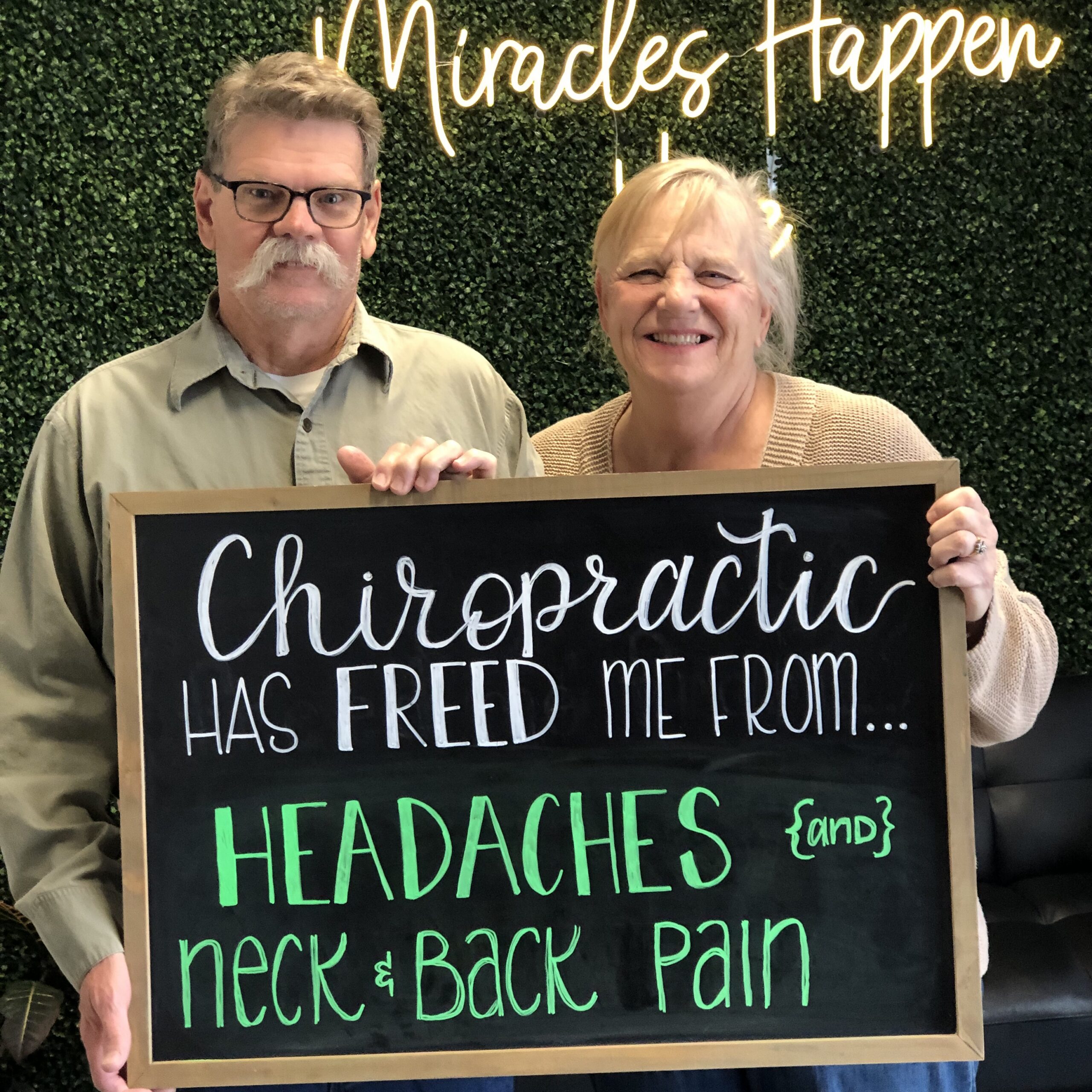 Two Legacy patients sharing their chiropractic result on a chalkboard