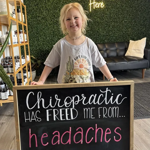 Young Legacy patient sharing a pediatric chiropractic chalkboard result
